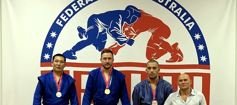 SAMBO coach standing with three competition medallists
